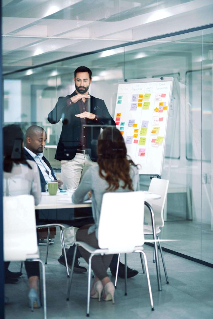 A group of professionals in a conference room, listening to a speaker during an IT corporate training session.